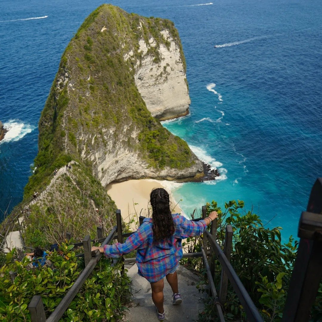 Voyageuse devant une plage et des falaises tropicales