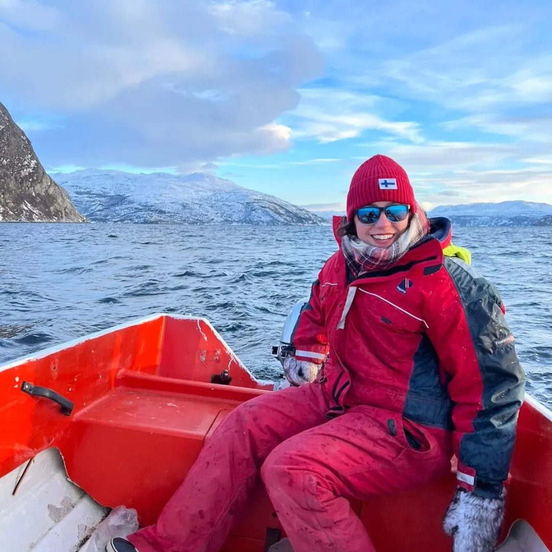 Laura sur un bateau avec des montagnes enneigées en arrière-plan